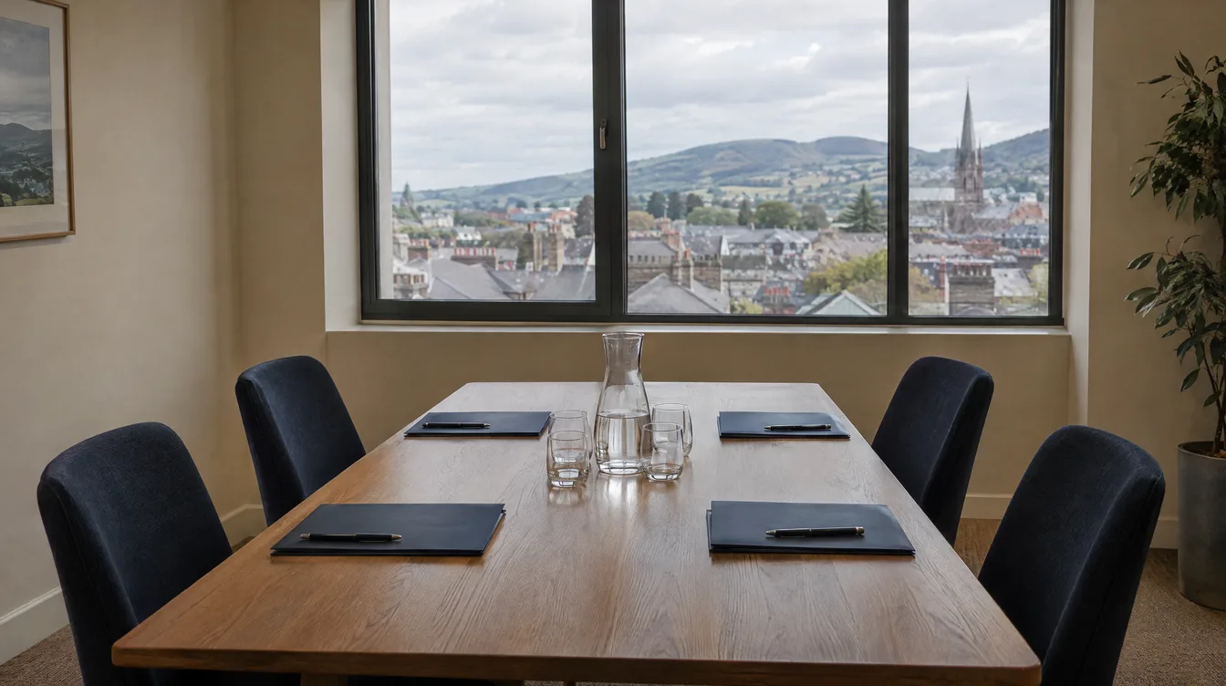 Meeting room table set with four navy folders and pens, with a window overlooking town rooftops and hills